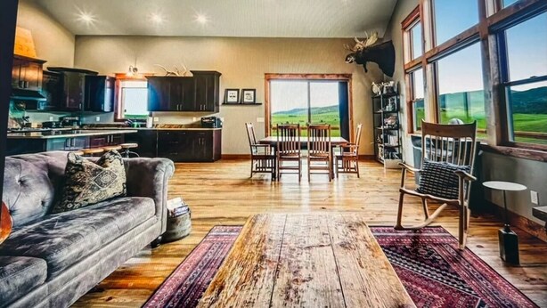 Ein großzügiges Wohnzimmer mit einem großen Holztisch, einem grauen Sofa und einem Essbereich mit Tisch und Stühlen.