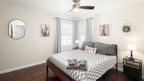 A neatly arranged bedroom with a bed, a nightstand, a ceiling fan, and a wall-mounted mirror. - Upgraded 2Bed/1B on Quiet Street w. Easy Access  to US99 (Fresno)
