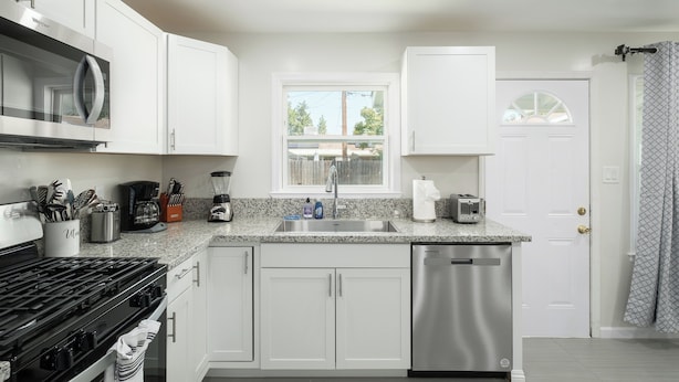 A modern kitchen with white cabinets, a stainless steel dishwasher, a built-in microwave, and a gas stove. - Upgraded 2Bed/1B on Quiet Street w. Easy Access  to US99 (Fresno)