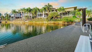 A waterfront hotel with a pool, palm trees, and modern buildings.