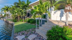 A modern hotel with a pool, palm trees, and a well-maintained garden.