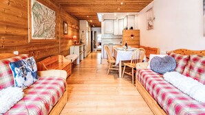 Un interior de cabaña acogedor con paredes de madera, una zona de comedor y una cocina.