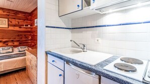 Una cocina compacta con armarios blancos, un fregadero y una estufa.