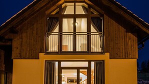 Ein zweistöckiges Holzhaus mit großen Fenstern und einem Balkon.
