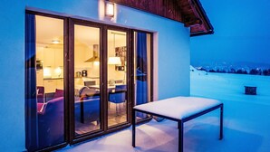 Ein modernes Gebäude mit einer Glastür, die zu einem Essbereich mit Tisch und Stühlen führt.