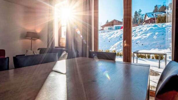 A modern dining area with a large table and chairs, large windows with a view of a snowy landscape and buildings. - Cosy apartment in villa for 5 guests with WIFI, TV, terrace and pets allowed (Kobylnice)