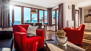 Ein modernes Wohnzimmer mit roten Sofas, einem Couchtisch und Meerblick durch große Fenster.