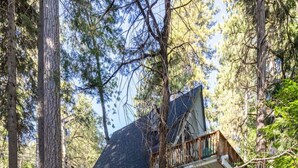 Une cabane dotée d’un toit à forte pente, d’une terrasse en bois et d’un escalier menant à un porche.