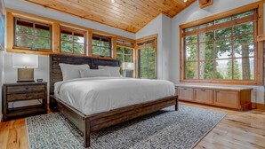 Une chambre avec un grand lit, une tête de lit en bois et un banc placé le long de la fenêtre.