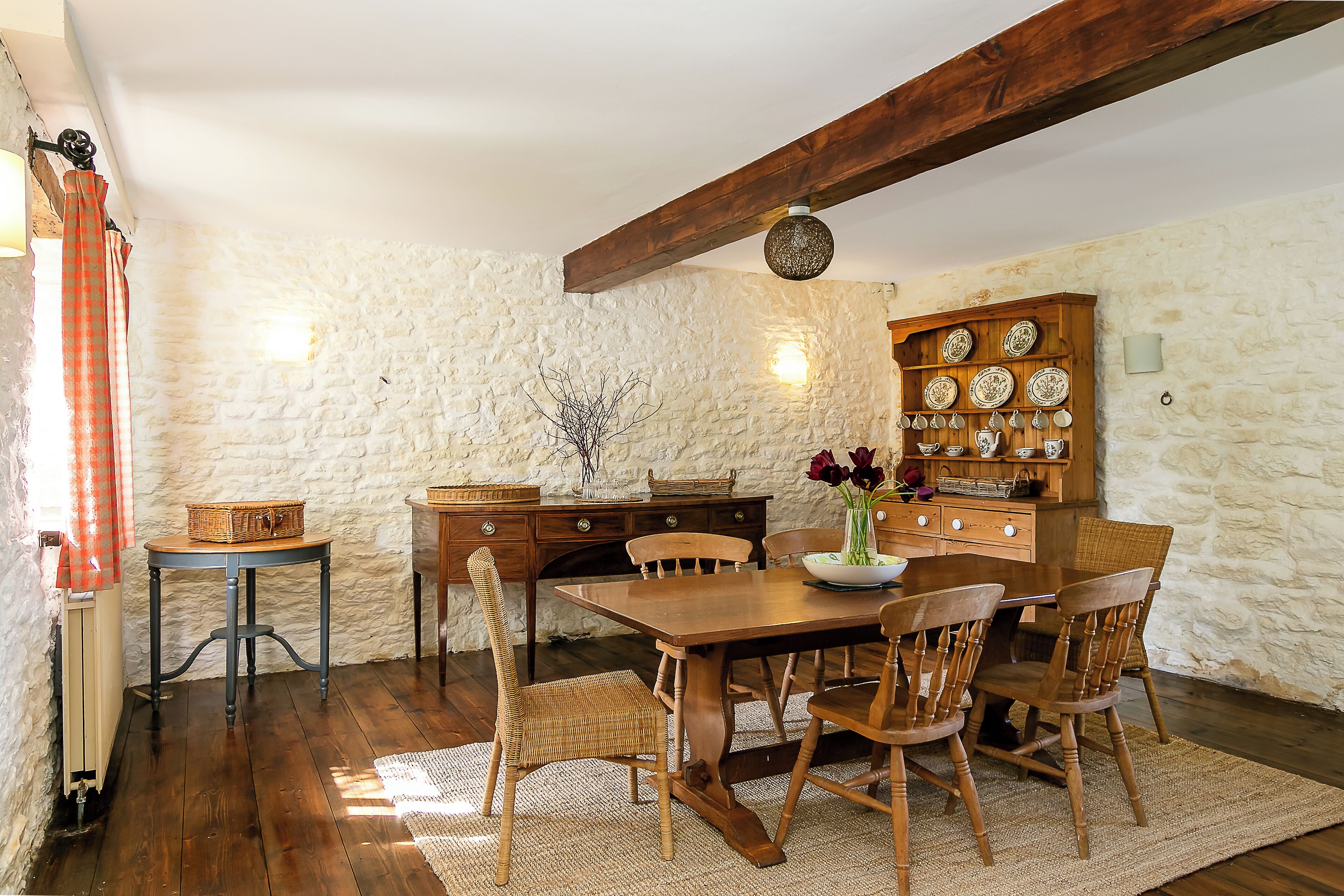 Un comedor rústico con una mesa de madera, sillas y una pared de piedra.