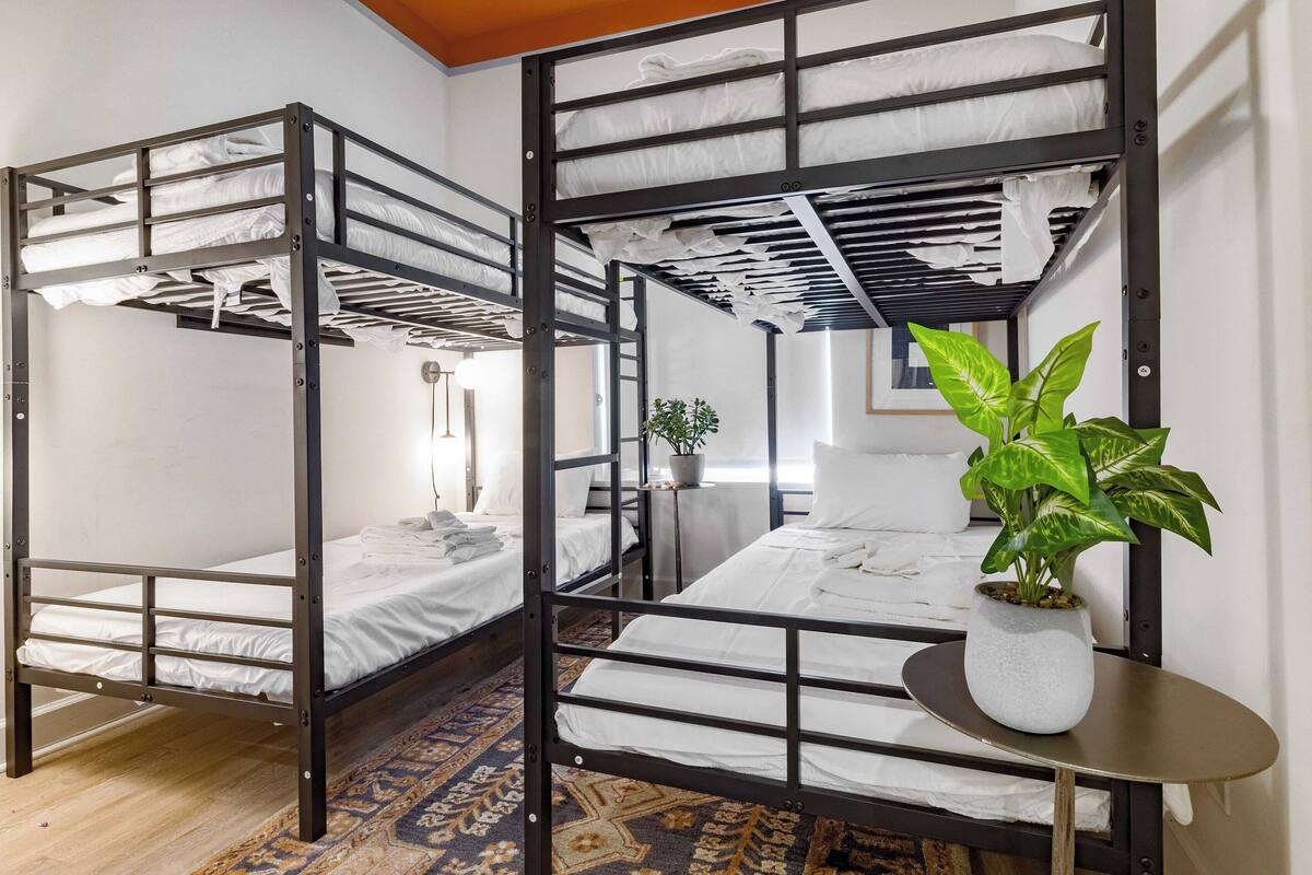 A room with two bunk beds, a small table with a potted plant, and a patterned rug.