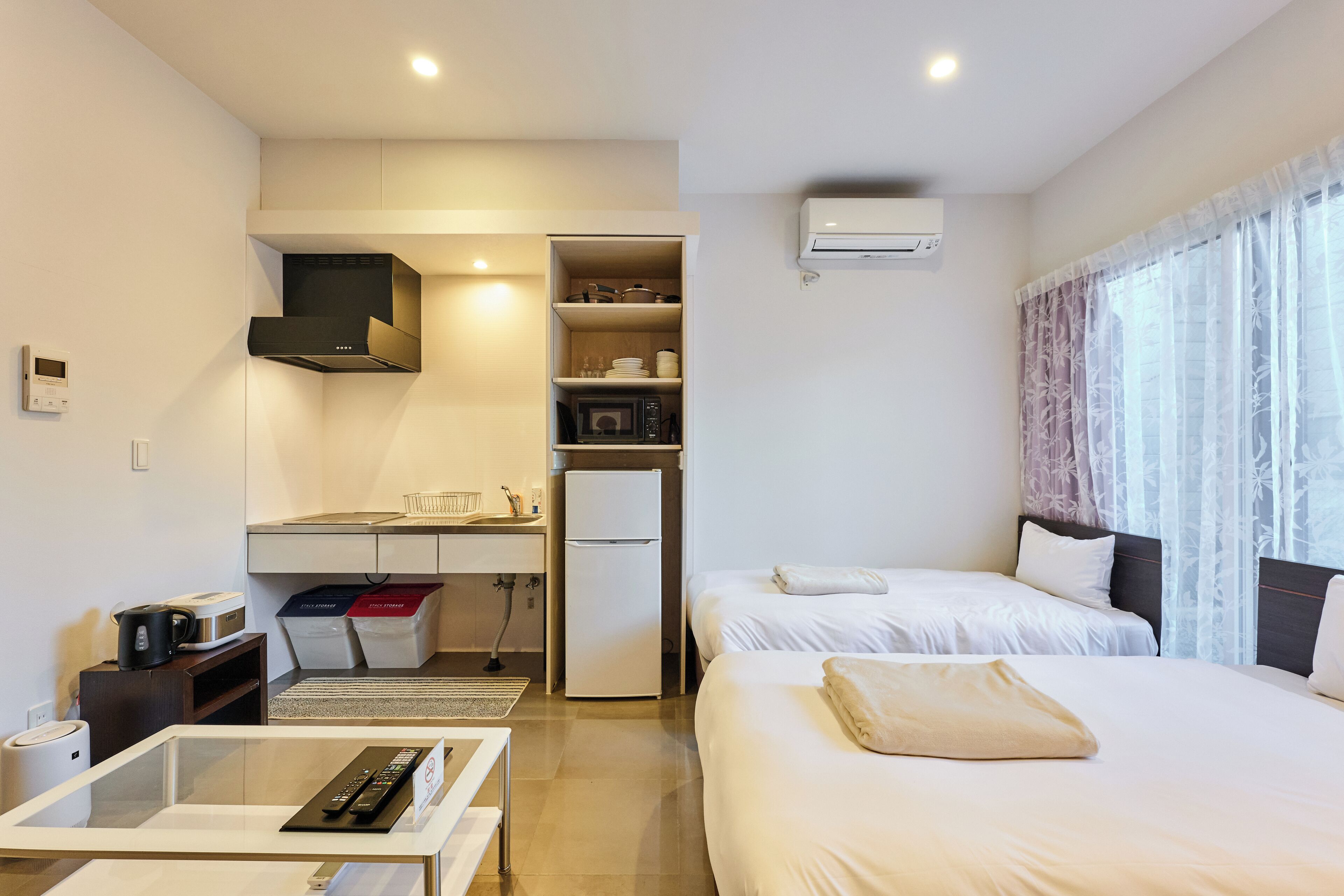 A hotel room with a bed, a desk with a computer, a microwave, and a small kitchenette.
