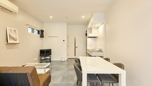 Un salon moderne avec un canapé blanc, une table basse en verre et un téléviseur.