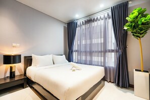 A modern hotel room with a neatly made bed, a bedside lamp, and a large window with sheer curtains. - The Lancaster Luxury Citypoint ANGIA By An Gia Hospitality (Ho Chi Minh City)