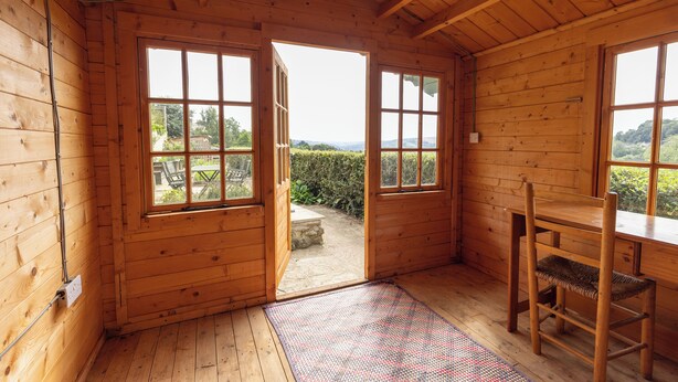 Una cabaña de madera con un ventanal grande y una silla de madera.