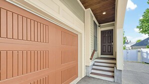 A garage door, a front door, and a set of stairs leading to a porch. - Inviting 3BR In Cambridge, Walk To T & Central Sq (Cambridge)