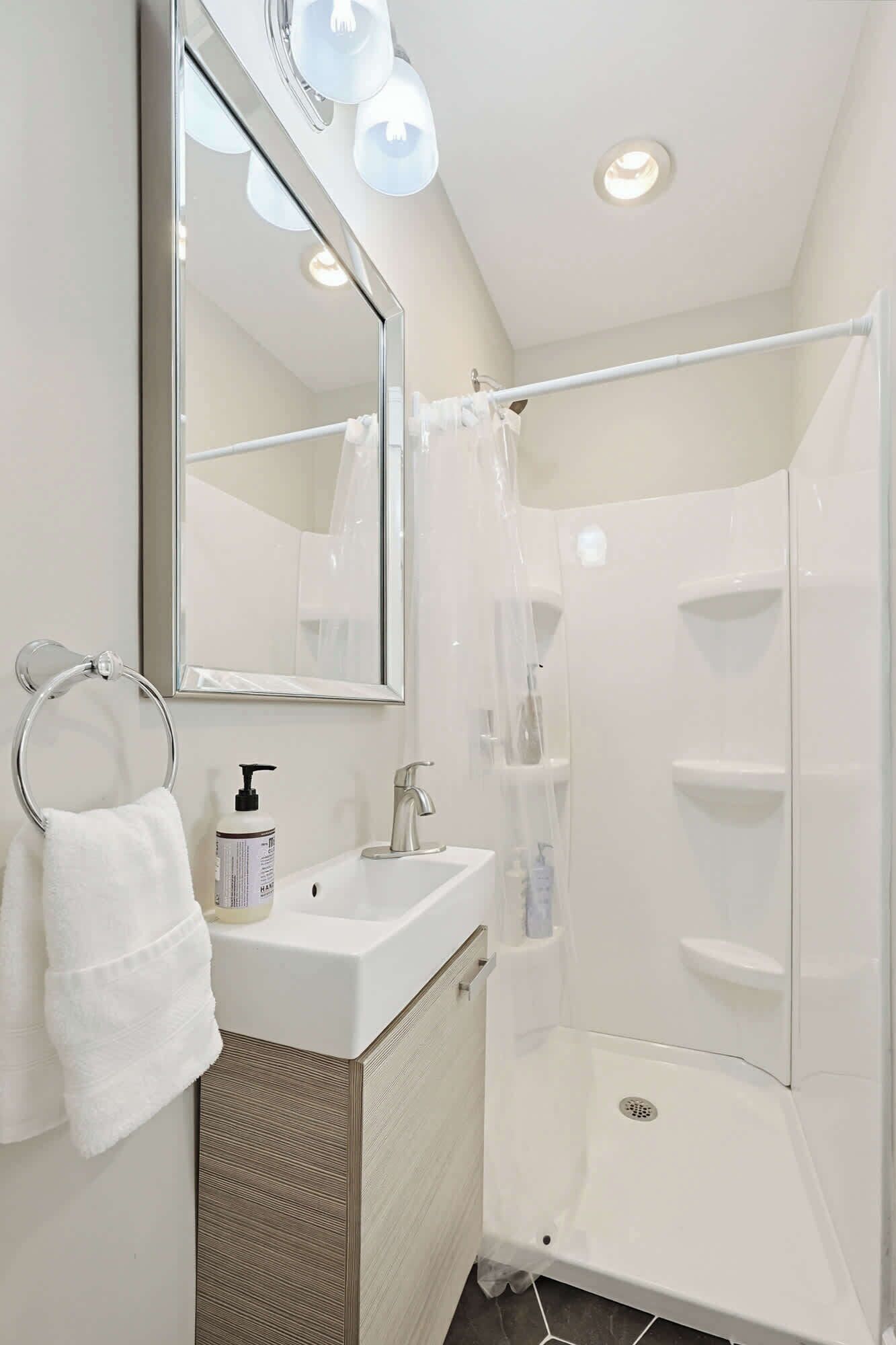 A modern bathroom with a glass shower enclosure, a sink with a mirror, and a towel rack.
