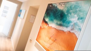 Una habitación con un cuadro grande de una playa, una puerta y un interruptor de luz en la pared.