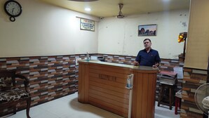 A hotel reception area with a wooden reception desk, a clock on the wall, and a sign requesting ID and address proof. - Trio hotel (Vasai)