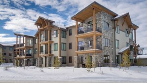 Un immeuble à plusieurs étages, doté d’une façade en pierre, de balcons et surplombant un paysage enneigé.