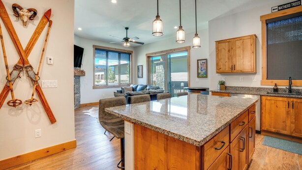 A modern kitchen with a large island, wooden cabinets, and pendant lighting. - Ski Season Escape! Fraser Condo & Hot Tub (Fraser)
