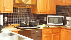 Una cocina con armarios de madera, un microondas, una estufa y un lavabo.