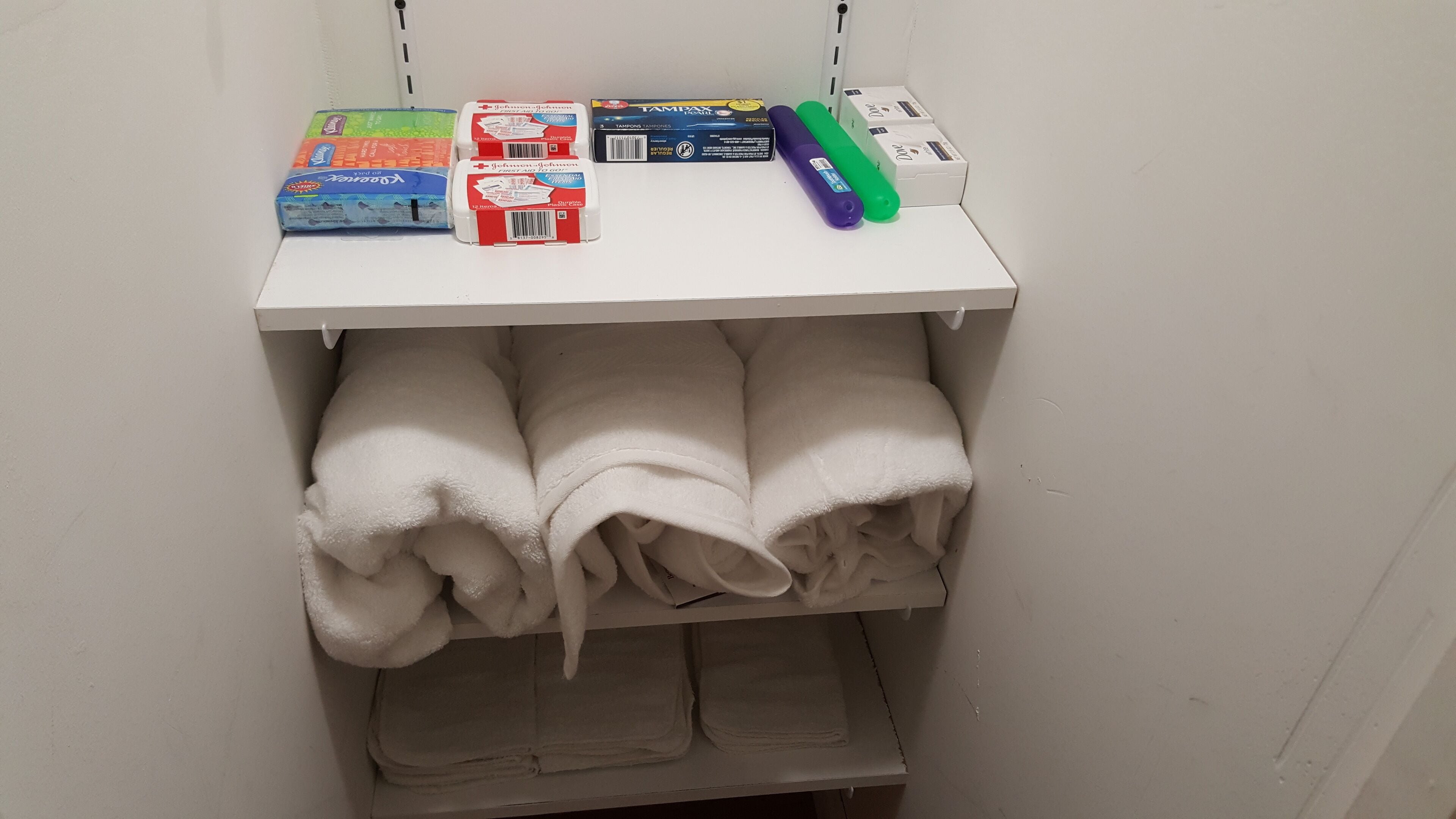 A storage shelf with folded towels and personal care items.