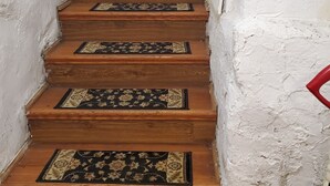 Una escalera de madera con alfombras estampadas en cada peldaño que lleva a una puerta blanca.