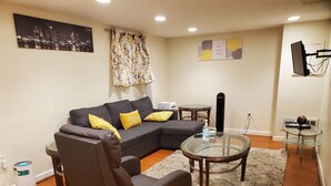 Una sala moderna con un sofá modular, una mesa de centro de cristal y una mesita redonda.