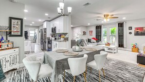 A modern kitchen with white cabinets, a dining area with a table set for four, and a ceiling fan. - Disney Day Trips! Lakefront Home w/ Heated Pool (Spring Hill)