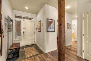 A hallway with a wooden bench, a door with a red sign, and framed pictures on the walls.