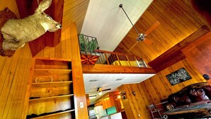 A spacious room with wooden floors, a staircase, a dining area, and a ceiling fan. - Spacious 4-bedroom house in charming Rockport with AC, WiFi BAR  (Rockport)