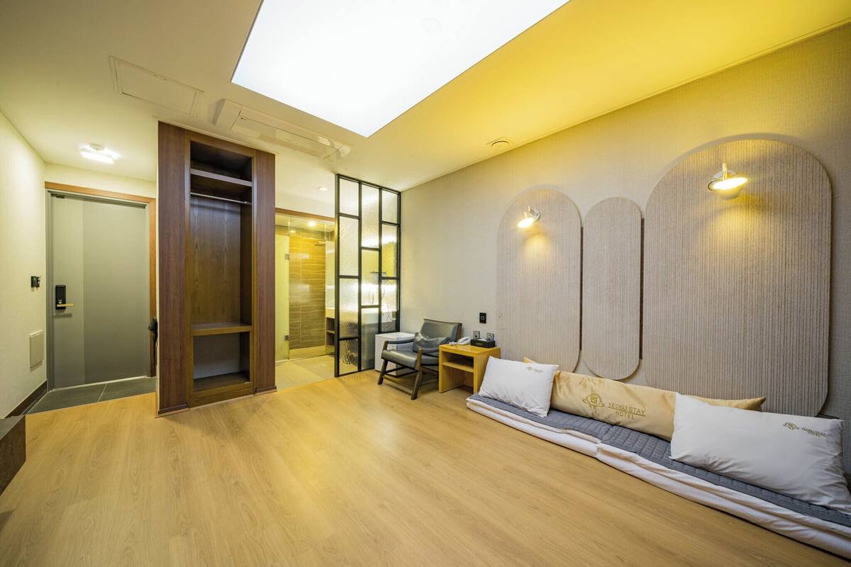 Una habitación de hotel moderna con tragaluces, sofá cama, escritorio y armario.