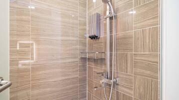 Un baño moderno con zona de ducha, paredes de azulejos y mampara de vidrio.