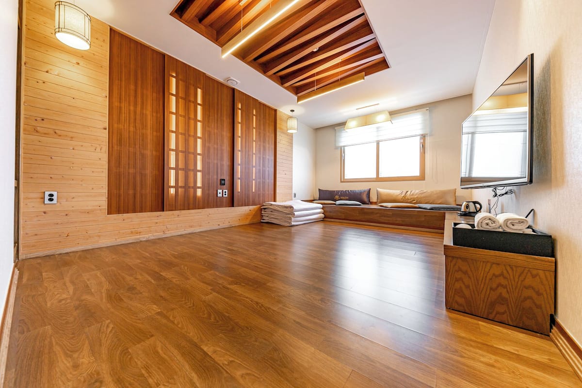 Una habitación amplia con suelo de madera, un rincón de descanso integrado y un espejo grande en la pared.