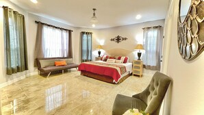 A spacious bedroom with a large bed, a sofa, and a chair.