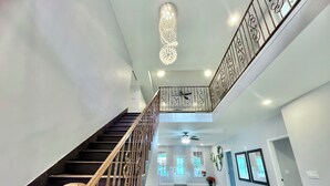 A spacious interior with a staircase leading to a second floor, a chandelier, and a ceiling fan.