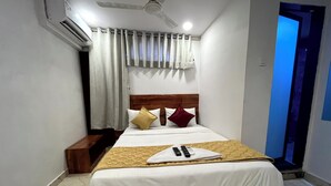 Una cama bien tendida con cabecera de madera, una mesita de noche y un control remoto sobre la cama.