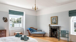 A bedroom with a bed, a chair, a fireplace, and a window. - Grade II Listed House in Central Exeter (Exeter)