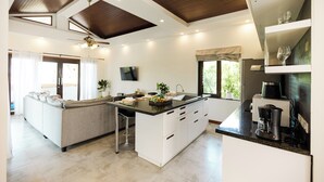 Una cocina moderna con una isla central, taburetes de bar y una cafetera.