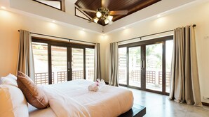 Un dormitorio amplio con una cama grande, puertas correderas de vidrio que dan a un espacio exterior y un ventilador de techo.