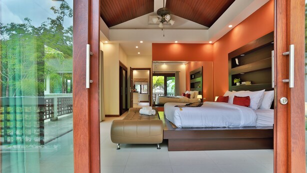 Un dormitorio moderno con una cama grande, un banco y vistas al exterior.