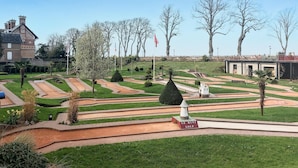 A landscaped garden with pathways, a monument labeled "LE MINTI GOLF", and a building with a clock tower in the background. - Stunning apartment in Berck plage with WiFi (Berck plage)