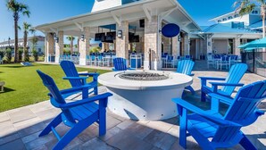 A poolside area with blue Adirondack chairs, a fire pit, and a covered bar area with stone pillars. - Sweet Retreat, Windsor Island Resort Near Orlando and Disney, by Shine Villas (Davenport)