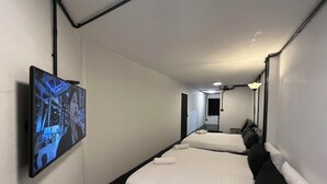 Une chambre d’hôtel avec deux lits, un téléviseur à écran plat fixé au mur et un couloir menant à la salle de bain.