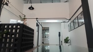 Un intérieur moderne agrémenté d’un ventilateur de plafond, de luminaires suspendus, d’une étagère en métal noir et de plantes en pot.