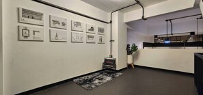 Un espace de bureau moderne avec un comptoir d’accueil, un tapis noir et blanc et des dessins d’architecture encadrés accrochés au mur.
