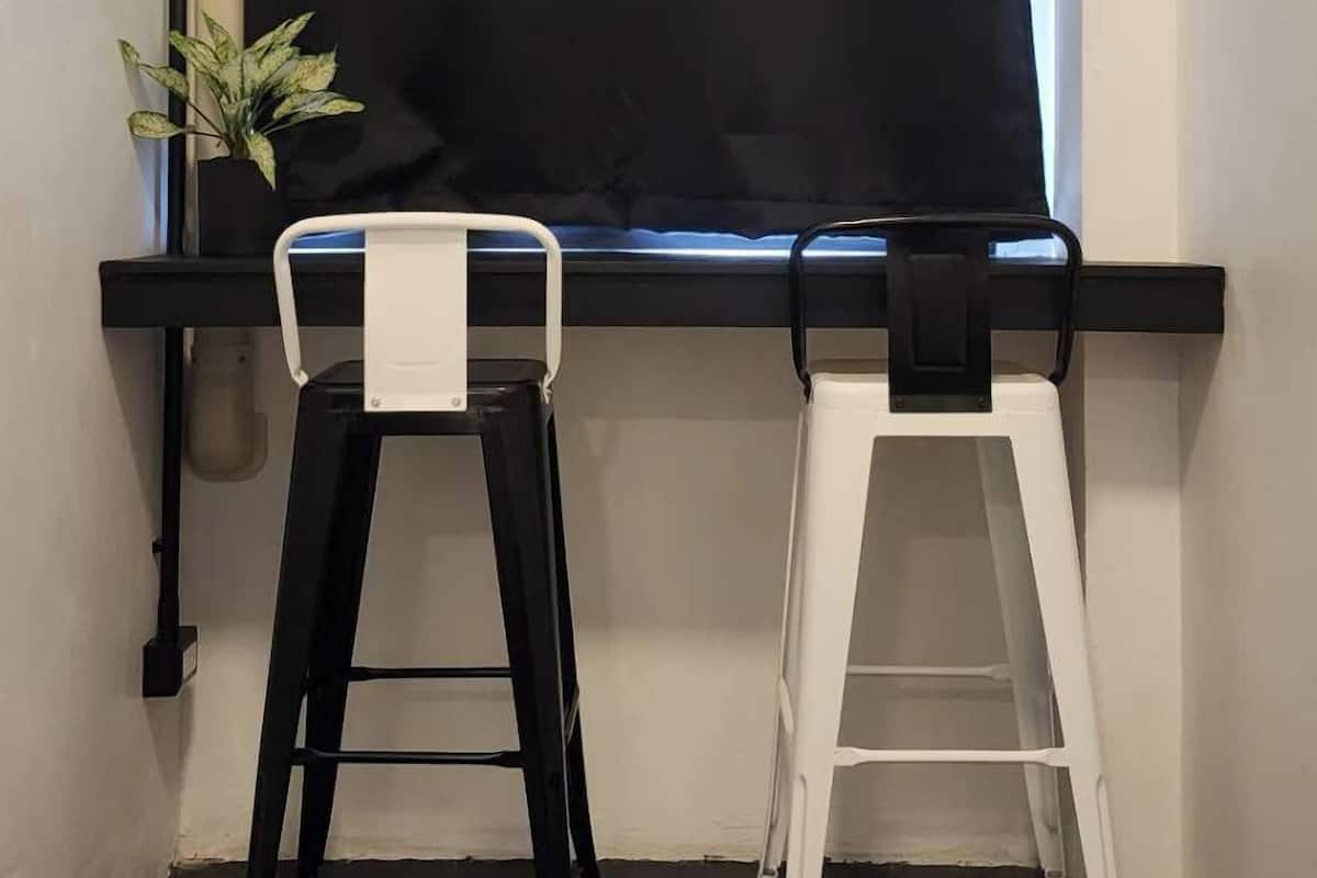 A room with a black curtain, a black and white stool, and a white stool.