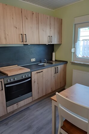 A kitchen with wooden cabinets, a built-in oven, a sink, and a window.
