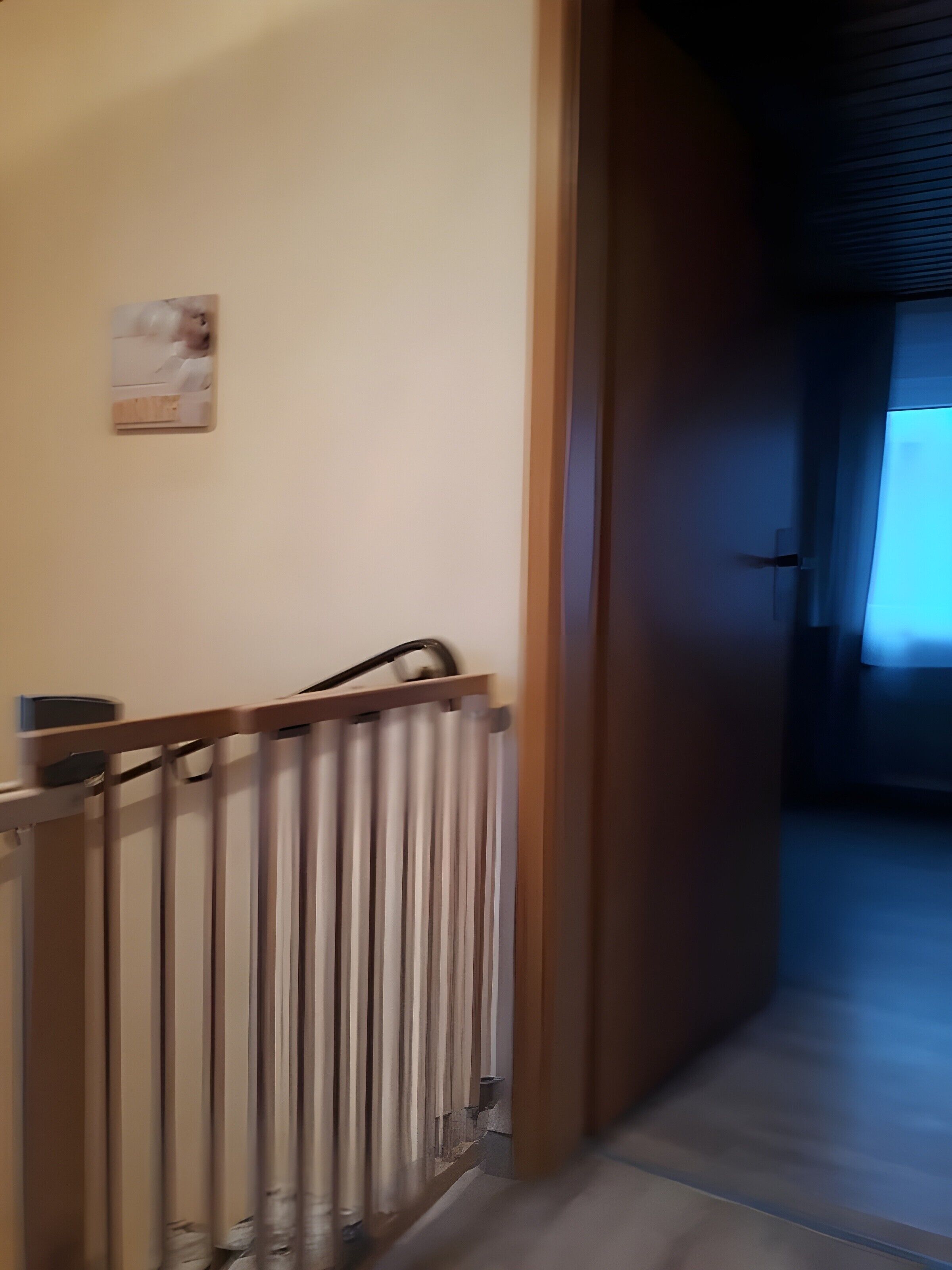 Un couloir avec un cadre de porte en bois, un radiateur et un petit tableau accroché au mur.